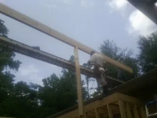 Carpenter setting a ridge beam over a new addition frame — Ice Dam Removal by Roofing Brothers in Attica