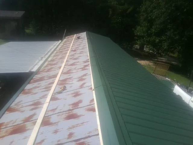 Old rusted panels beside newly installed green metal roofing — Wind Damage Roof Repair by Roofing Brothers in Attica